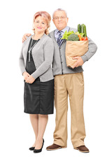 Mature couple posing with a bag of groceries