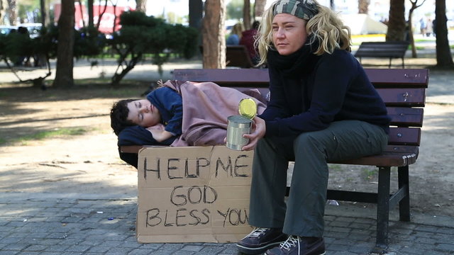 Homeless, sick family begging on a park bench