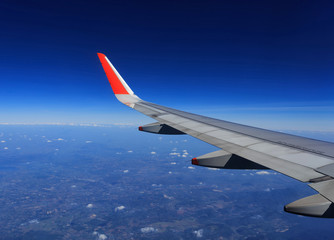 Fototapeta premium Wing of an airplane flying above the clouds