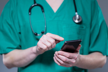 Close up of doctor in uniform using phone