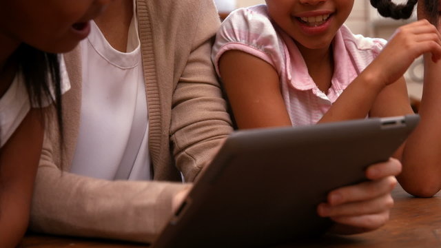 Teacher looking at tablet with pupils