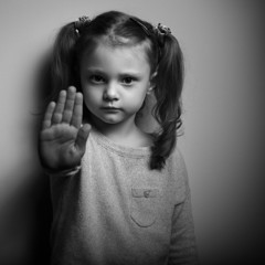 Stop violence against kids. Serious kid showing hand stop sign.