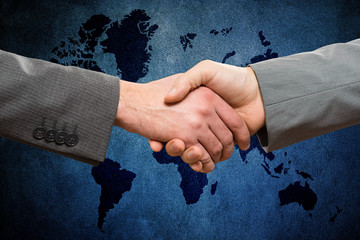 Handshake between business men against world map