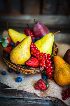 Pears with berries on wooden background