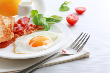 Bacon and eggs on color wooden table background