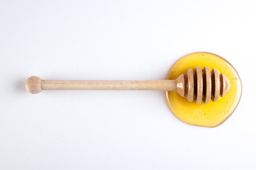 honey flowing down from a wooden stick isolated on white