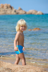 Fototapeta na wymiar Cute little smiling boy plays on the beach