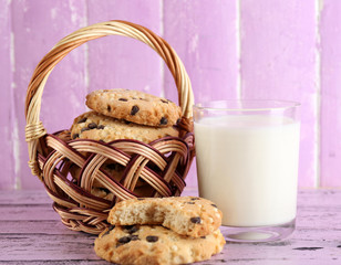 Tasty cookies and glass of milk on color wooden background