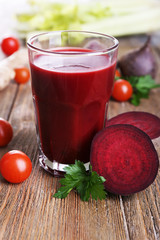 Glass of beet juice with vegetables on wooden table close up