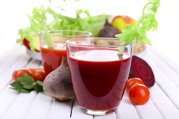Glasses of beet juice with vegetables on wooden table closeup