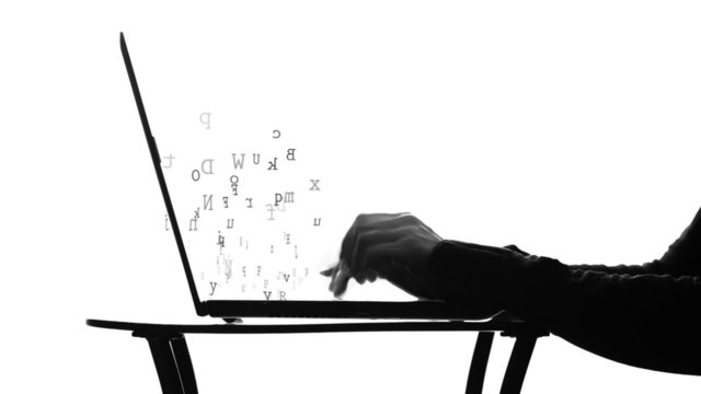 hands typing on a laptop at a desk (looping)
