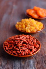 Dried fruits in small plates on rustic wooden table background