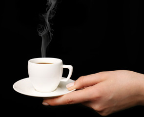 Female hand holding cup of coffee on black background