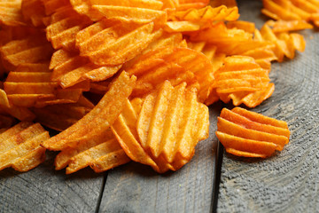 Delicious potato chips on wooden table close-up