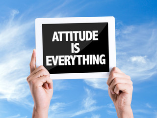 Tablet pc with text Attitude is Everything with sky background