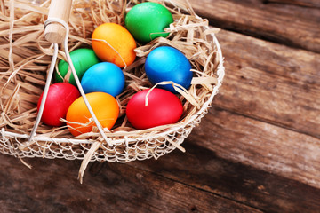 Easter eggs in basket on vintage wooden planks background