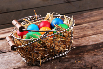 Easter eggs in basket on vintage wooden planks background