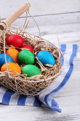 Easter eggs in basket on vintage wooden planks background