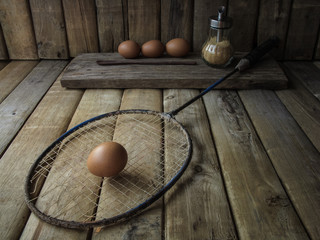 Egg on badminton racket wtih wood table background