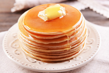 Delicious pancakes with honey on plate on table close-up