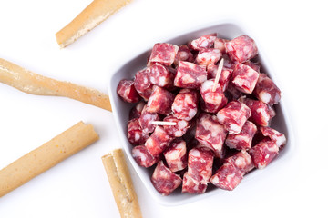dry sausage cutted in small pieces in a bowl and bread sticks
