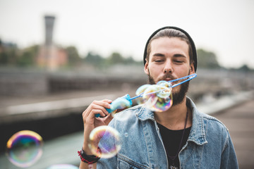 young handsome bearded hipster man blowing bubbles soap - obrazy, fototapety, plakaty