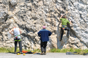 Three people climbing up a rock face