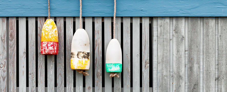 lobster buoys on weathered wood fence. Banner format
