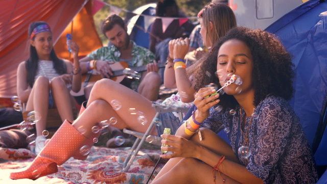 In high quality format carefree hipster blowing bubbles in tent
