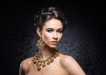 Young, beautiful and rich woman in jewels of gold and stones