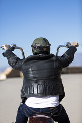 Naklejka premium rear view of a chopper motorcyclist riding .