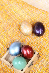 Colorful easter eggs in wood box on bamboo weave sheet.