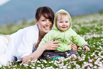 Happy mother are playing with baby in flowers field