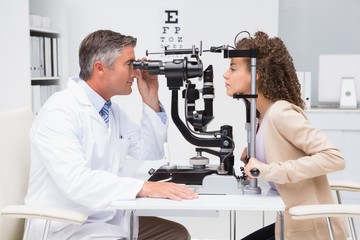 Woman doing eye test with optometrist - obrazy, fototapety, plakaty