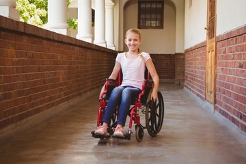 Girl sitting in wheelchair in school corridor