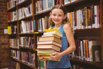 Cute little girl carrying books in library
