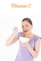 Vitamin c against good looking woman eating a bowl of salad