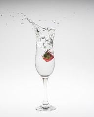 Strawberry falls deeply under water with a splash