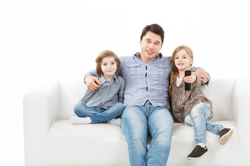 Family sitting on sofa smiling at camera on white background