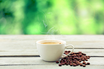 Cup of coffee on wooden table on green background