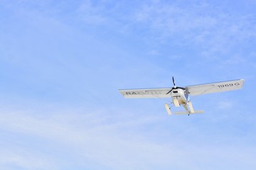 The plane flies against a blue sky with clouds