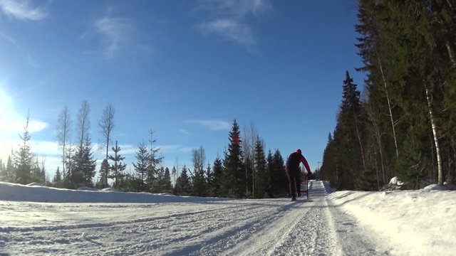 Man riding kicksledge on road