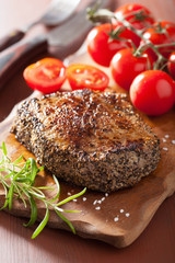 beef steak with spices and rosemary on wooden background