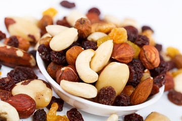 Mixed nuts and sultanas on a plate on a white background