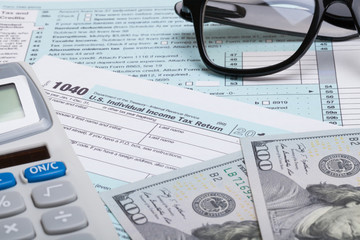 US 1040 Tax Form, calculator, glasses and dollars - studio shot