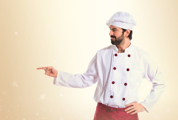 Chef pointing to the lateral over white background