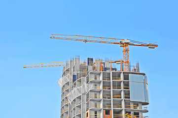Crane and building construction site against blue sky