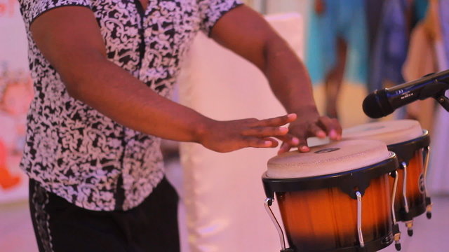 Young male percussionist playing cuban drums against black