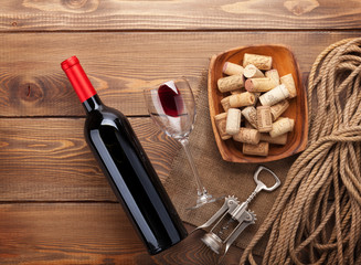 Red wine bottle, wine glass, bowl with corks and corkscrew