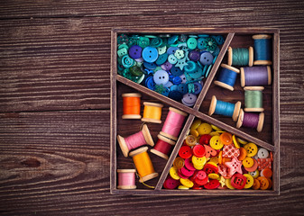 threads and buttons  arranged in a grunge wooden box